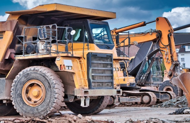 Mobilität-Nutzfahrzeuge wie ein Bagger und ein Kipplader stehen nebeneinander auf einer Baustelle