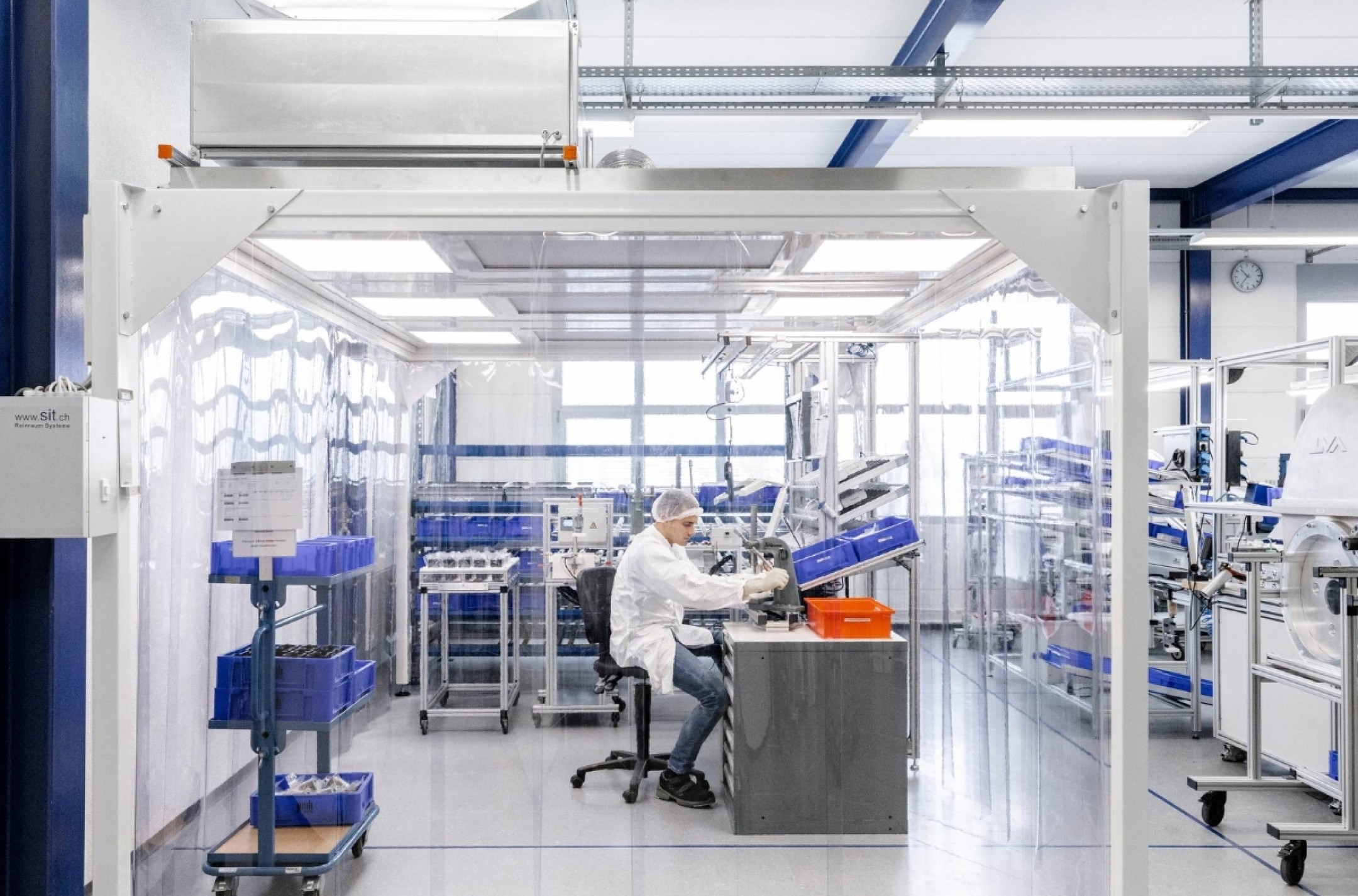 Mann montiert in Schutzkleidung mechanische Fertigungskomponenten in Reinraum nach ISO13485