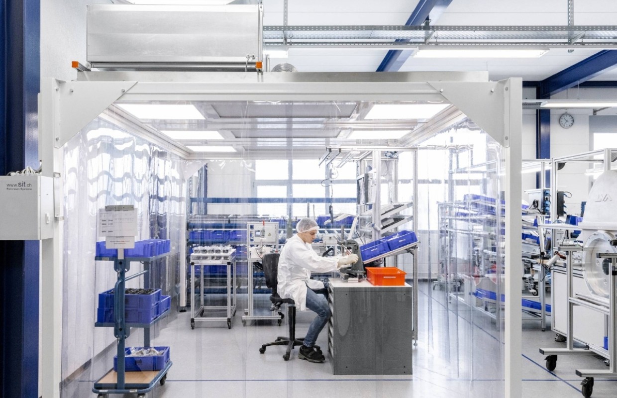 Mann montiert in Schutzkleidung mechanische Fertigungskomponenten in Reinraum nach ISO13485