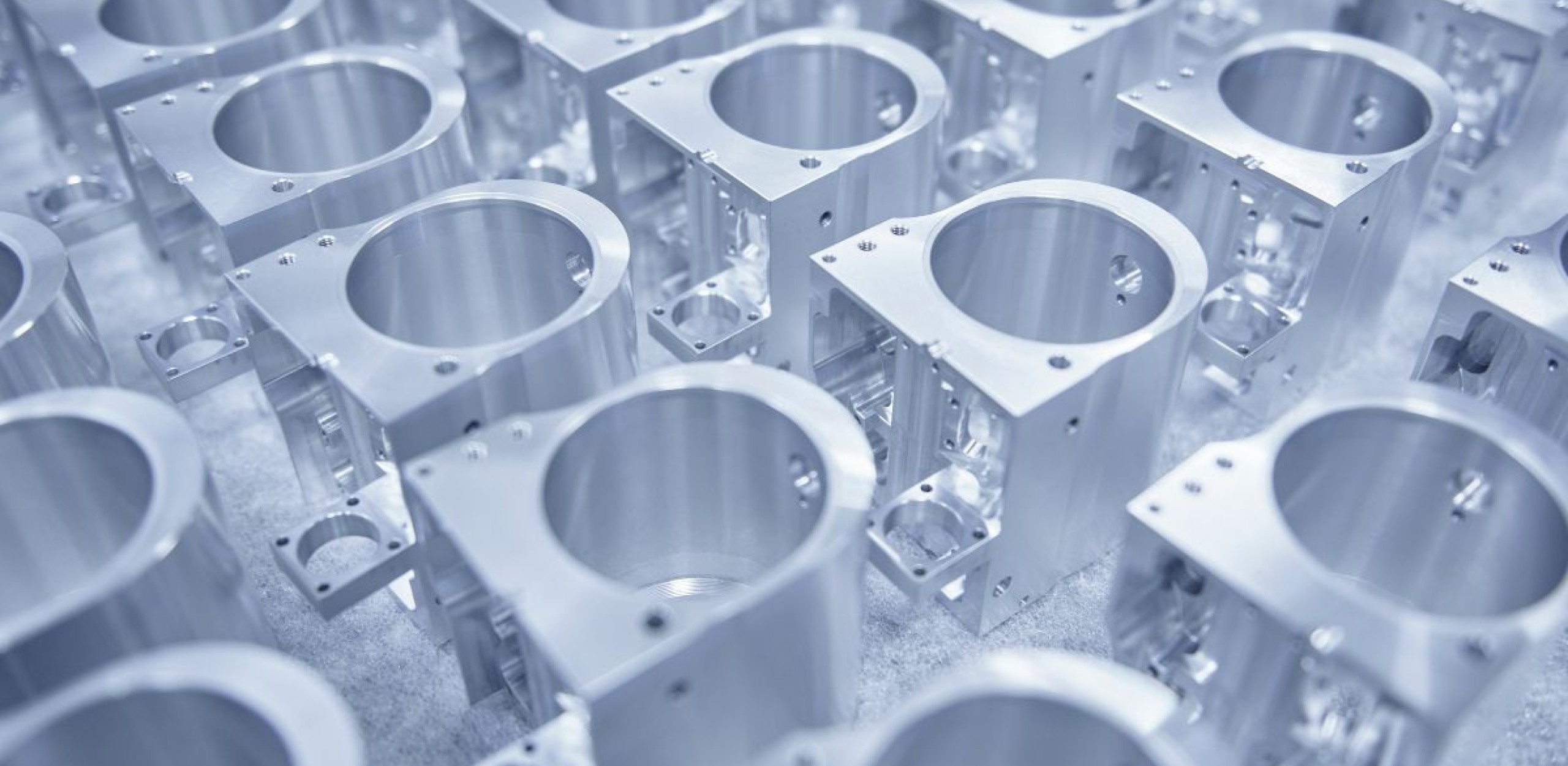 CNC gefertigte Werkstücke aus Metall liegen neben einander auf einer weissen Unterlage